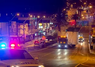 A large lorry transports part of a TBM down a Sydney street at night time.