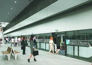 An artist's impression of commuters walking outside of Sydney Metro's Waterloo Station. Pink cherry blossom trees line the station entrance.