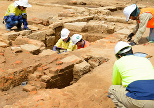 Five construction workers inspecting the ground for archaeological artefacts during the excavation at Sydney Metro's White Hart Inn site.