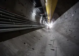 An on the ground view inside the tunnel of construction with a construction worker impacting the work at Sydney Metro's Bella Vista Station.