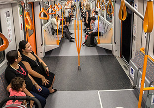 Commuters inside one of Sydney Metro's trains showing the orange interior. 