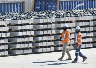 An on the ground view of two construction workers walking alongside Sydney Metro Trains Facility (SMTF) worksite at Marrickville Station. 