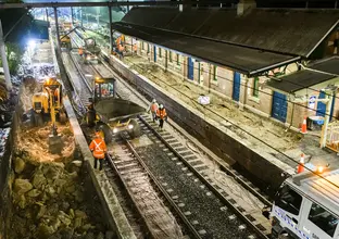 A bird's eye view of construction workers in orange high-vis performing night time track works at Canterbury Station.