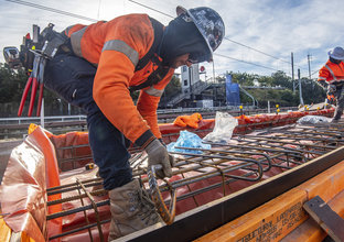 A close up view of a construction worker laying metal rods in place on site at Dulwich Hill Station.