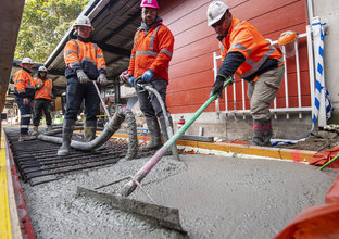 An on the ground view of construction workers laying the concrete on the tracks at Sydney Metro's Marrickville Station.