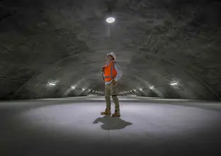 On the ground image of a construction worker looking up inside the cavern in Sydney Metro's Barangaroo Station. 