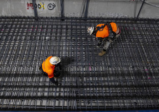 Two construction workers assemble the track slab steel reinforcement works at Pitt Street Station cavern.