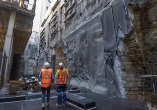 Two construction workers look up at the waterproofing works at Pitt Street North site.