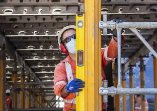 A construction worker is vertically leveling a steel beam at Waterloo Station.