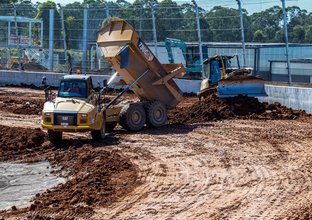 A dump truck unloads dirt at the construction site of the new Sydney International Speedway.