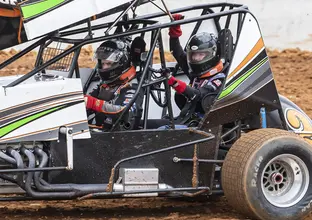 Two people are inside a race car driving in in the dirt track at the new Eastern Creek Speedway.