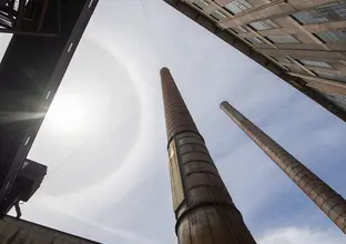 A view from the ground looking up at the sky at large smoke stacks at White Bay Power Station.