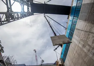 A ground up view of a crane lifting a concrete panel down to B3 level at Sydney Metro's Waterloo Station. 