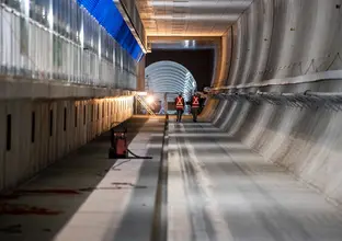 A view of two construction workers walking inside the underground tracks at Victoria Cross Station.