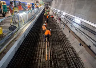 Several construction workers are working on the tracks inside Victoria Cross station.