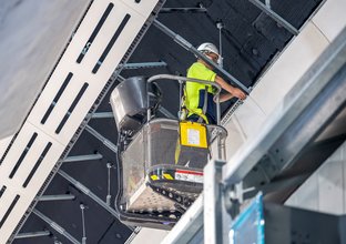 A construction worker stands on a cherry picker lift while working inside the cavern at Sydney Metro's Victoria Cross station.