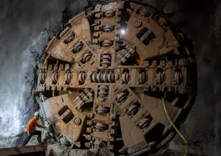 Construction worker inspecting Tunnel Boring Machine (TBM) Kathleen breaking through at Sydney Metro's Blues Point tunnel access site. 