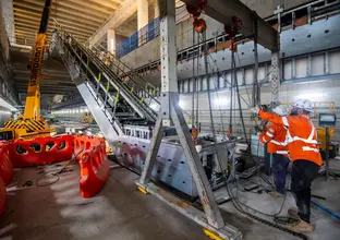 Two construction workers installing an escalator underground at Barangaroo Station.