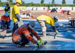 An on the ground view of construction workers levelling wet concrete on Sydney Metro's Eastern Creek Station precast site. 