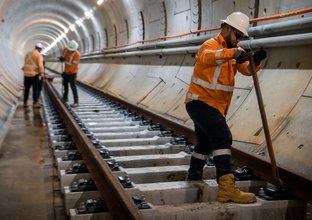 Construction workers putting in concrete railway sleepers onto underground tunnel railway line at Sydney Metro's Blue Point site between Victoria Cross and Barangaroo Station. 