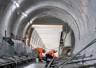 On the ground view of construction workers laying the final track down in the underground tunnel at Sydney Metro's between Central and Pitt Street stations.