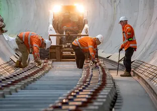 On the ground view of construction workers installing noise attenuating sleepers in the underground tunnel at Sydney Metro's between Martin Place and Barangaroo stations.