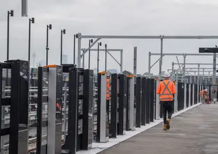 Construction worker walking along platform with newly installed platform screen doors at Sydney Metro's Sydenham Station