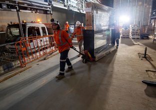 Construction workers delivering a platform screen door through a construction site
