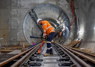 Construction worker building skeleton track in underground crossover cavern