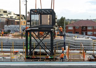 Crane and construction workers positioning a 45-metre-long footbridge into place at  Dulwich Hill Station
