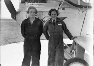 Peggy Kelman (left) with Nancy-Bird Walton (right) standing in front of a plane in pilot gears 