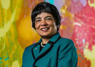 Dr Marlene Kanga standing infront of a colorful background, smiling at the camera