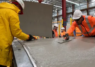 2 workers are pouring cement to produce a precast segment