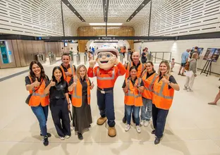 Mascot surrounded by people in high vis gear with their thumbs up