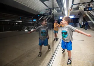 Young boy walking past the metro gates smiling