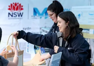 A Sydney Metro employee is handing out a bag to a stakeholder in an event