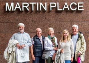 Group of 5 elderly people in front of the Martin Place sign outside the station
