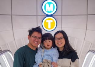 Couple and young child in front of M and T neon sign