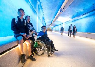Parents and young boy in a wheelchair in the blue lit up tunnel