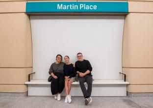 Parents and child sitting in front of a Martin Place sign