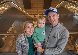 Couple holding their son in front of the escalators that are going down