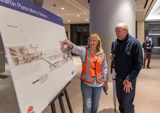 Metro worker in high-vis showing community member information on a board