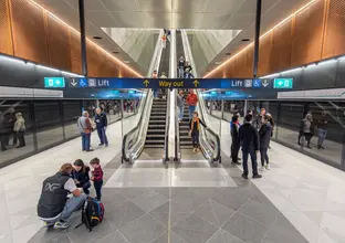 Image from the platforms showing way out sign and the escalators with members of the community walking around