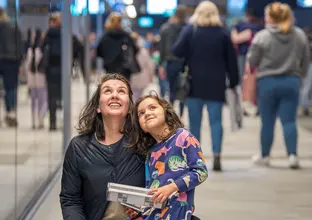 Daughter sitting on mothers knee both looking up in the platform