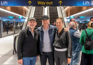 Group of three standing in from of the way out sign in front of the escalators