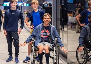 Child in wheelchair next to two of his friends in front of the platform screen doors