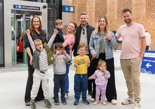 Group of adults and children gathered at the station posing for a photo