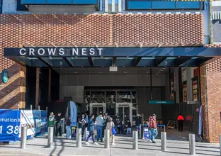 Image from outside of the station showing the Crows Nest sign and people walking in to enter