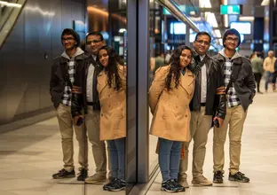 Three people standing next to the platform screen doors smiling for the picture