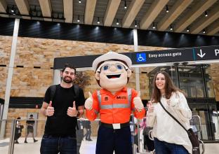 two people taking a photo with the male Metro mascot 